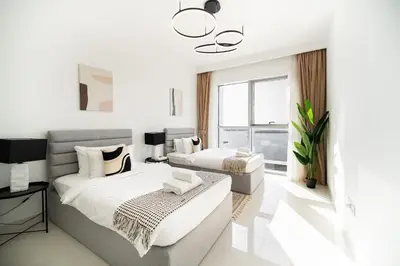 a white bedroom with two beds and a window at SettlerHomes - Breathtaking View With Private Beach in Dubai