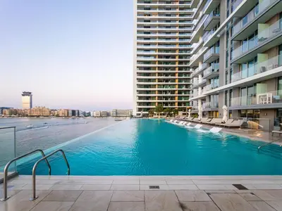 a large swimming pool next to a large building at SettlerHomes - Breathtaking View With Private Beach in Dubai