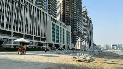a beach with chairs and umbrellas in front of a building at Beachfront 2-BDR, High floor, Sea and Palm View, Beach Access in Dubai