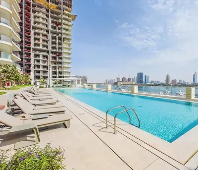 a swimming pool with lounge chairs and a building at Beachfront 2-BDR, High floor, Sea and Palm View, Beach Access in Dubai