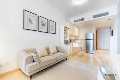 a living room with a couch and a kitchen at Unbeatable Price, Luxury 1BR, Limited Time Offer by Deluxe Holiday Homes in Dubai