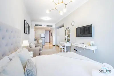 a white bedroom with a large bed and a desk at Unbeatable Price, Luxury 1BR, Limited Time Offer by Deluxe Holiday Homes in Dubai