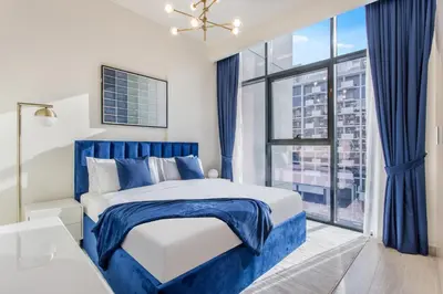 a blue and white bedroom with a large window at Elegant 1BR Retreat in Riviera 36 Near Downtown in Dubai