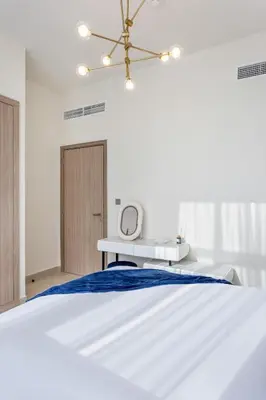 a white bedroom with a bed and a mirror at Elegant 1BR Retreat in Riviera 36 Near Downtown in Dubai