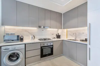 a kitchen with white cabinets and a washer and dryer at Elegant 1BR Retreat in Riviera 36 Near Downtown in Dubai