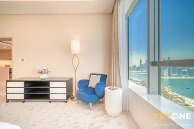 a bedroom with a blue chair and a desk and a window at Iconic One Bedroom Panoramic Palm Views in Dubai