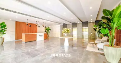 a lobby with potted plants and a table at Stunning Luxury 1BR - Modern with Pool View - JVC in Dubai