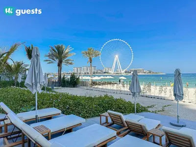 a beach with chairs and a ferris wheel in the background at HiGuests - Ocean Views and Comfort in La Vie, JBR in Dubai
