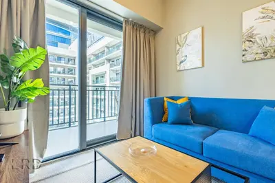 a living room with a blue couch and a large window at Cozy & Radiant 1BR Business Bay in Dubai