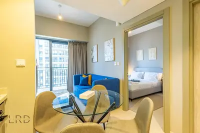 a living room with a bed and a glass table at Cozy & Radiant 1BR Business Bay in Dubai
