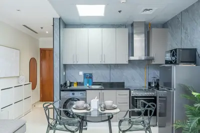 a kitchen with white cabinets and a table and chairs at Escape24 Cozy 1BR near Dubai Malll & Burj Khalifa in Dubai