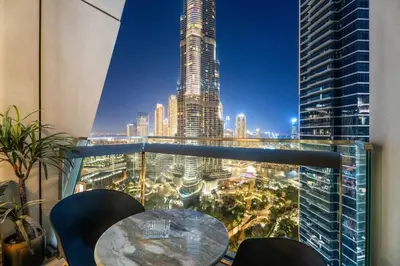 a table and chairs on a balcony with a view of a city at Luxe 3BR Retreat, Balcony Burj & Fountain Views, Prime Downtown Stay in Dubai