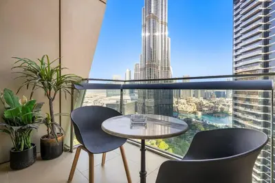 a table and two chairs in a room with a large window at Luxe 3BR Retreat, Balcony Burj & Fountain Views, Prime Downtown Stay in Dubai