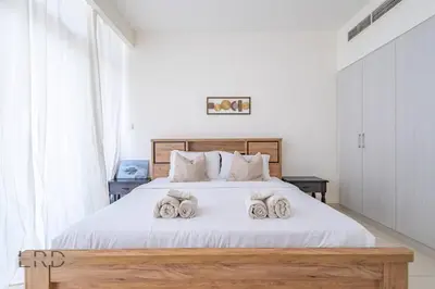 a bedroom with a white bed with towels on it at Modern & Vibrant 1BR Dubai Hills in Dubai