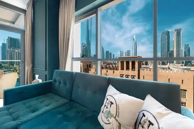 a blue couch in a room with a large window at Iconic Burj Khalifa Views from Luxury 1BR Home in Dubai