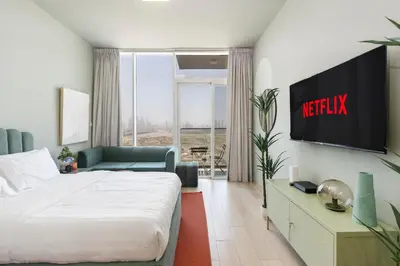 a hotel room with a bed and a television at Cosy Studio Apartment in Bloom Towers, Jumeirah Village Circle in Dubai