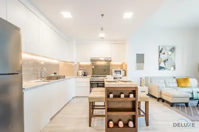 a kitchen with white cabinets and a living room at Delightful 2BR Apartment in Town Square Safi 1A, Dubailand by Deluxe Holiday Homes in Dubai