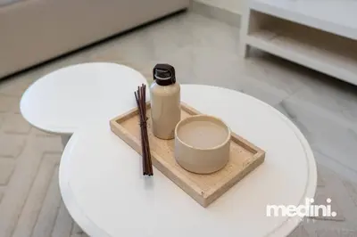 a white table with a bottle and a cup on it at Studio in Samana Golf Avenue - Dubai in Dubai