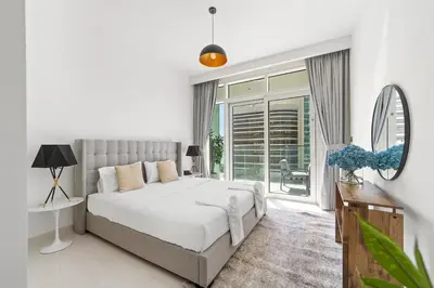 a white bedroom with a bed and a large window at Spacious 2 BHK next to the Beach - Sunrise Bay in Dubai