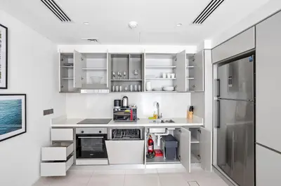 a kitchen with white cabinets and a refrigerator at Spacious 2 BHK next to the Beach - Sunrise Bay in Dubai