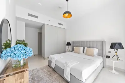 a white bedroom with a large bed and a table at Spacious 2 BHK next to the Beach - Sunrise Bay in Dubai