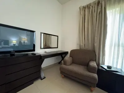 a living room with a television and a chair at ASHRI HH, Studio in JVC Dana Tower in Dubai
