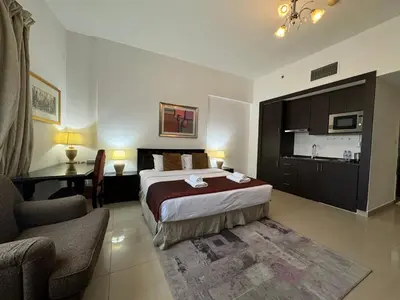 a bedroom with a bed and a desk and a kitchen at ASHRI HH, Studio in JVC Dana Tower in Dubai