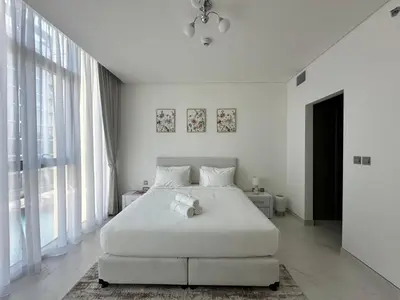 a white bedroom with a large bed and large windows at Spacious 1bedroom W Lagoon In Al Maktoum City in Dubai