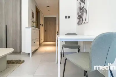 a kitchen with a table and chairs in a room at Oxford Boulevard - Studio - JVC Dubai in Dubai
