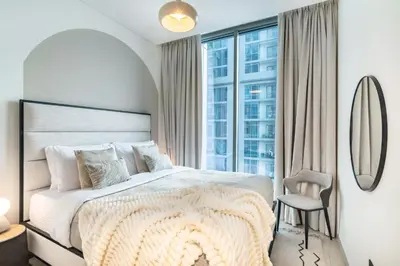 a white bedroom with a large bed and a chair at The Smarft Concierge - Sobha Creek Vista in Dubai