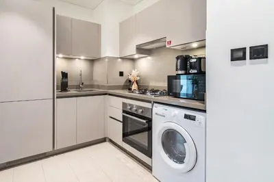 a white kitchen with a washer and dryer at The Smarft Concierge - Sobha Creek Vista in Dubai