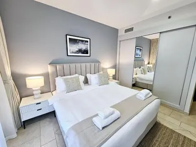 a bedroom with a large white bed with two towels at Spacious 1-BR close to Barasti Beach and Marina Walk in Dubai