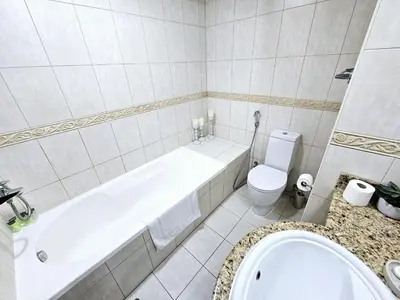 a white bathroom with a tub and a toilet at Spacious 1-BR close to Barasti Beach and Marina Walk in Dubai