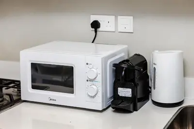 a white microwave sitting on a counter next to a coffee maker at DAMAC Vera 1BR with Downtown & Burj Khalifa View in Dubai