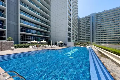 a swimming pool in front of a tall building at DAMAC Vera 1BR with Downtown & Burj Khalifa View in Dubai