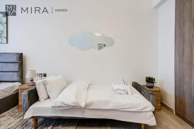 a bed with white sheets and pillows in a room at Mira Holiday Homes - Fully Furnished Studio in JLT in Dubai