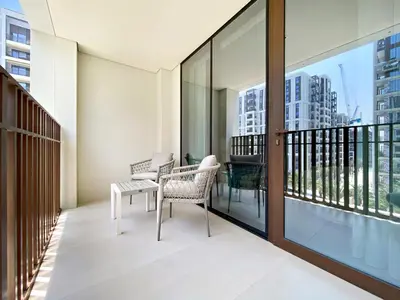 a balcony with two chairs and a table and windows at Silkhaus Chic 1BDR In Unique Neighborhood in Dubai