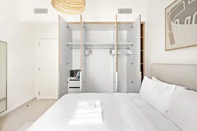a bedroom with a white bed and a closet at Silkhaus Chic 1BDR In Unique Neighborhood in Dubai