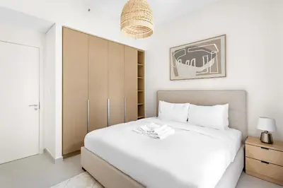 a bedroom with a large white bed and a cabinet at Silkhaus Chic 1BDR In Unique Neighborhood in Dubai