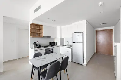 a kitchen with a table and chairs and a refrigerator at Elegant - 1BR - 8 MIN Burj Khalifa & Dubai Mall in Dubai