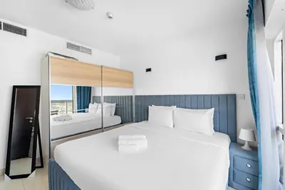 a bedroom with a large white bed and a mirror at 1BR Apartment minutes from Mall of the Emirates in Dubai