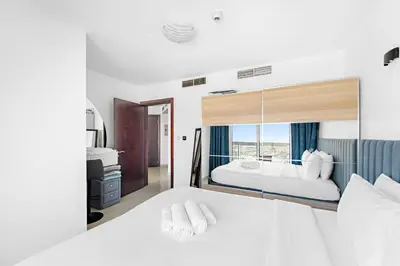 a bedroom with a large white bed with a large mirror at 1BR Apartment minutes from Mall of the Emirates in Dubai