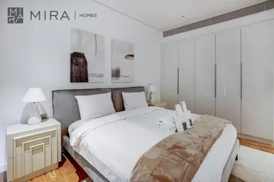 a white bedroom with a bed and a night stand at Mira Holiday Homes - Lovely 3 bedroom in Bluewaters with sea view in Dubai