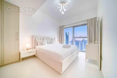 a white bedroom with a bed and a large window at Burj Royale - Burj Khalifa View, Downtown Dubai in Dubai
