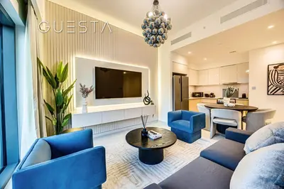a living room with blue chairs and a tv at Burj Royale - Burj Khalifa View, Downtown Dubai in Dubai