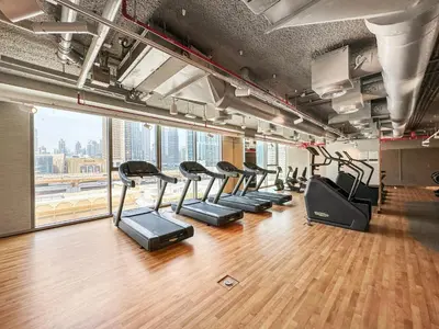 a gym with a row of treadmills at 3BR plus maid's room with Burj Khalifa views in Dubai