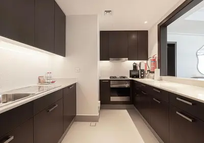 a kitchen with dark brown cabinets and white counter tops at SmartStay at Opera Grand - Stunning Burj Khalifa Views - Brand New Luxury Residences in Dubai