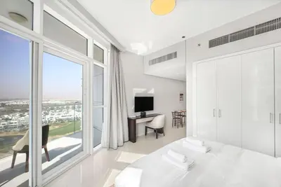a bedroom with a white bed and a large window at Tranquil Studio with Golf View in Dubai
