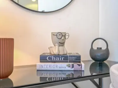 a stack of books on a glass table with a mug on top at EasyGo - Unbeatable Deals on Urban Rentals in Riviera 16 in Dubai
