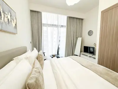 a white bedroom with a large bed and a window at EasyGo - Unbeatable Deals on Urban Rentals in Riviera 16 in Dubai